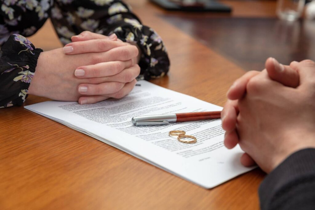 Two wedding rings and a pen resting on a legal document between a divorcing couple, representing property division in an Oakland divorce.